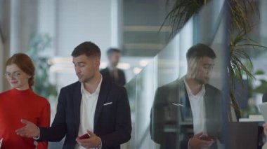 Modern bir girişim şirketinin dinamik ortamında, yönetici genç iş arkadaşı ile yürürken bir tartışma içine girer, işbirliği ve yenilik ruhunu yansıtır.