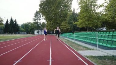 Stadyumun kırmızı raylarında egzersiz yaparken koşan iki zinde erkek ve kadın. Yüksek kalite 4 bin yavaş çekim görüntüsü