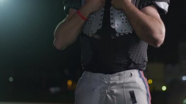 Bir Amerikan futbolcusunun yakın plan portresi yoğun bir antrenmandan sonra terliyor, atletizm ve kararlılık sergiliyor. Sporla ilgili içerik ve motivasyonel görseller için ideal