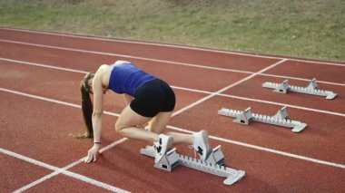 Atletizm atletizm sprint yarışı koşucusu koyu bir arka planda, stadyumun pistinde spor ayakkabılarla koşu koşusuna çıkıyor. Yavaş çekim