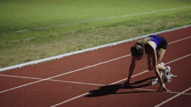 Atletizm atletizm sprint yarışı koşucusu koyu bir arka planda, stadyumun pistinde spor ayakkabılarla koşu koşusuna çıkıyor. Yavaş çekim