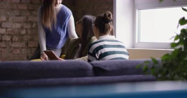 Kadın iş adamları pencere kenarında iş birliği yapıyor, fikirleri tartışıyor ve tablet üzerinde beyin fırtınası yapıyorlar. Modern bir ofiste işbirliği, yaratıcılık ve takım çalışması kavramı