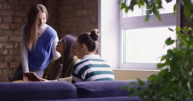 Kadın iş adamları pencere kenarında iş birliği yapıyor, fikirleri tartışıyor ve tablet üzerinde beyin fırtınası yapıyorlar. Modern bir ofiste işbirliği, yaratıcılık ve takım çalışması kavramı