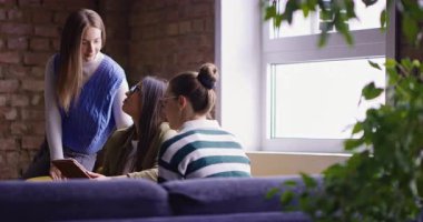 Kadın iş adamları pencere kenarında iş birliği yapıyor, fikirleri tartışıyor ve tablet üzerinde beyin fırtınası yapıyorlar. Modern bir ofiste işbirliği, yaratıcılık ve takım çalışması kavramı