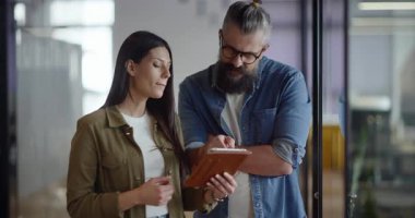 Yaratıcı milenyumlar, sıradan iş adamları, küçük işletme sahipleri, sosyal medya stratejisi ve marka geliştirme üzerinde çalışan modern, açık bir ofis ortamında dijital tabletle