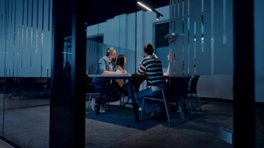 Genç profesyonellerden oluşan çeşitli bir ekip modern bir ofis konferans salonunda işbirliği yapıyor. İş adamları, yenilikçi bir e-ticaret geliştirmek için dizüstü bilgisayar kullanarak strateji, teknoloji ve planlamayı tartıştılar