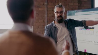 Moden ofis alanı, iş dünyasından profesyonellerden oluşan bir ekip canlı tartışmalara girişiyor ve stratejik fikirleri paylaşıyor, modern kurumsal açık alanların merkezinde işbirliği ve yenilik sergiliyor.