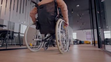 Tekerlekli sandalyede engelli bir iş adamı, modern bir ofiste takım çalışmasının, dahil olmanın ve güçlenmenin gücünü ortaya koyan destekleyici meslektaşlarıyla çevrilidir.. 