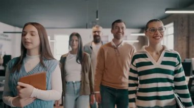 Modern bir açık mekan ofisinin iş ekibi birlikte yürüyor. Çeşitli iş adamları tartışırken gülümsüyor. Başarılı karma ırk meslektaşları yeni bir projede işbirliği yapıyorlar