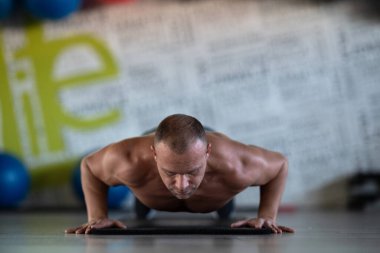 Spor salonunda şınav çeken kaslı bir adam. Güç, dayanıklılık ve kendini spora adamış.