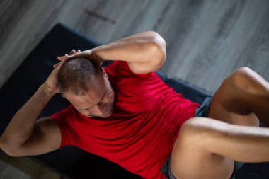 Spor salonunda mekik çeken kaslı bir adam. Çekirdek dayanıklılığına ve fitness hedeflerine ulaşmaya odaklanıyor.. 