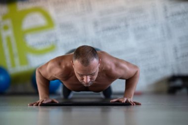 Spor salonunda şınav çeken kaslı bir adam. Güç, dayanıklılık ve kendini spora adamış.