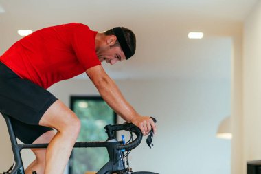 Modern bir oturma odasında triatlon bisikleti süren bir triatloncu.. 