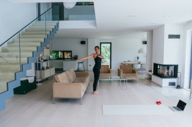 Genç Güzel Kadın Egzersiz, Esneme ve Egzersiz Yogası Parlak Sunny House 'da Video Çağrı Konferansı aracılığıyla Antrenörle. Sağlıklı Yaşam Tarzı, Refah ve Farkındalık Konsepti.