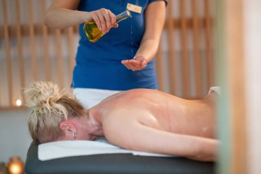 Profesyonel bir masaj terapisti ellerine aromatik yağ dökerek huzurlu bir kaplıca ortamında rahatlatıcı ve canlandırıcı bir masaj seansı hazırlar. 