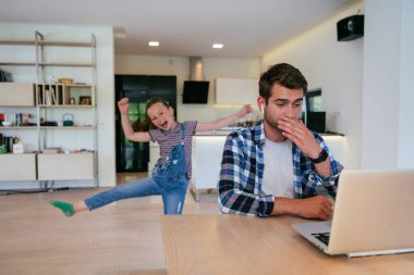 Evden çalışıyorum. Kızı, modern oturma odasında otururken bilgisayarında iş görüşmesi yaparken babasının sözünü kesiyor.