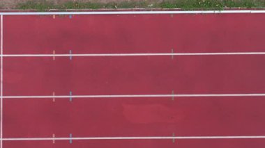 Boş koşu pistinin yukarıdan aşağıya görüntüsü, el değmemiş şeritleri, temiz sınırları ve geniş açık alanı gösteriyor, pistin dinginliğini ve yalnızlığını vurguluyor, spor ve uygunluk için ideal.