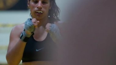 Kickboks yapan kadın boksör yumruklarını çalıştırırken kız hızlı saldırırken spor salonunda günlük antrenman yapıyor. Yüksek kalite 8K görüntü