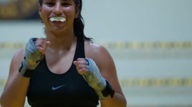 Kickboks yapan kadın boksör yumruklarını çalıştırırken kız hızlı saldırırken spor salonunda günlük antrenman yapıyor. Yüksek kalite 8K görüntü
