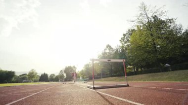 İş adamı atletizm pistinde koşarken engelden atlıyor. Yüksek kalite 4 bin yavaş çekim görüntüsü