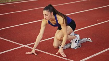 Atletizm atletizm sprint yarışı koşucusu koyu bir arka planda, stadyumun pistinde spor ayakkabılarla koşu koşusuna çıkıyor. Yavaş çekim
