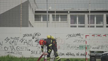 İtfaiyecilerden oluşan özel bir ekip bir itfaiye aracından hortumları alıyor ve tehlikeli bir tehlikeyle mücadele etmedeki cesaret ve profesyonel uzmanlıklarını sergileyerek, yanan bir yangını söndürmek için tehlikeli bir göreve çıkıyorlar.