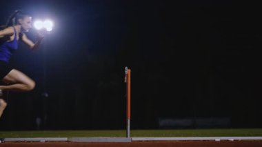 Dişi sporcu bir engele doğru koşuyor, engelli koşuyor, yüksek hızda bariyerin üzerinden atlıyor bir yarışta koşarken. Hız Rampası Efektli Süper Yavaş Sinema Görüntüsü.