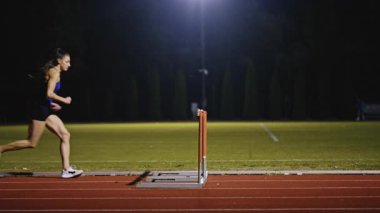 Dişi sporcu bir engele doğru koşuyor, engelli koşuyor, yüksek hızda bariyerin üzerinden atlıyor bir yarışta koşarken. Hız Rampası Efektli Süper Yavaş Sinema Görüntüsü.