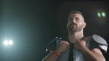 Bir Amerikan futbolcusunun yakın plan portresi yoğun bir antrenmandan sonra terliyor, atletizm ve kararlılık sergiliyor. Sporla ilgili içerik ve motivasyonel görseller için ideal