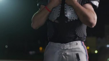 Bir Amerikan futbolcusunun yakın plan portresi yoğun bir antrenmandan sonra terliyor, atletizm ve kararlılık sergiliyor. Sporla ilgili içerik ve motivasyonel görseller için ideal