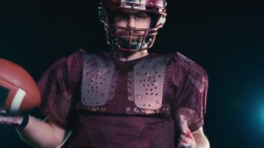 Sahada top atma ve yakalama pratiği yapan Amerikalı bir futbolcu, üniforma ve kask giyerek, dinamik hareketler ve kararlı bir atletik duruş ile becerilerini geliştirmeye odaklandı.