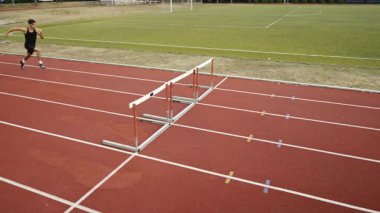 Stadyuma atletik zinde bir çift erkek ve kadın fırlatılıyor. Sıcak bir yaz öğleden sonrasında engellerin üzerinden atlamak. Yavaş Hareket İzleme Görüntüsü. 