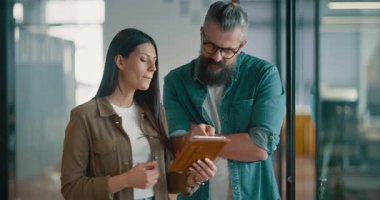 Yaratıcı milenyumlar, sıradan iş adamları, küçük işletme sahipleri, sosyal medya stratejisi ve marka geliştirme üzerinde çalışan modern, açık bir ofis ortamında dijital tabletle