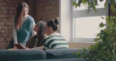 Kadın iş adamları pencere kenarında iş birliği yapıyor, fikirleri tartışıyor ve tablet üzerinde beyin fırtınası yapıyorlar. Modern bir ofiste işbirliği, yaratıcılık ve takım çalışması kavramı