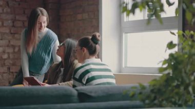 Kadın iş adamları pencere kenarında iş birliği yapıyor, fikirleri tartışıyor ve tablet üzerinde beyin fırtınası yapıyorlar. Modern bir ofiste işbirliği, yaratıcılık ve takım çalışması kavramı