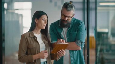 Yaratıcı milenyumlar, sıradan iş adamları, küçük işletme sahipleri, sosyal medya stratejisi ve marka geliştirme üzerinde çalışan modern, açık bir ofis ortamında dijital tabletle