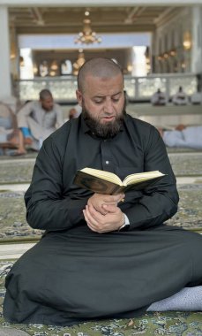 Mekke, Suudi Arabistan - 2 Mayıs 2024: Genç adam, Hac ve Umrah hacı Mescidi Haram 'da oturuyor ve Kuran okuyor, Suudi Arabistan' daki Büyük Cami. Hac 2024. Üst görünüm