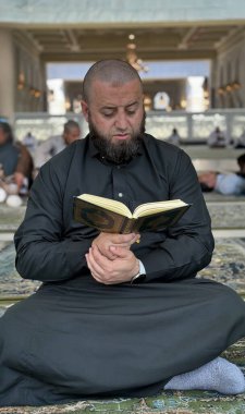 Mekke, Suudi Arabistan - 2 Mayıs 2024: Genç adam, Hac ve Umrah hacı Mescidi Haram 'da oturuyor ve Kuran okuyor, Suudi Arabistan' daki Büyük Cami. Hac 2024. Üst görünüm