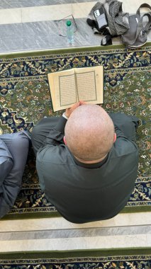 Mekke, Suudi Arabistan - 2 Mayıs 2024: Genç adam, Hac ve Umrah hacı Mescidi Haram 'da oturuyor ve Kuran okuyor, Suudi Arabistan' daki Büyük Cami. Hac 2024. Üst görünüm