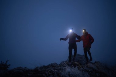 İki sporcu gece boyunca engebeli dağ patikalarında koşar, far ve kış giysileri giyerek, soğuk, sisli arazide kararlılık ve dayanıklılıkla yol alırlar..