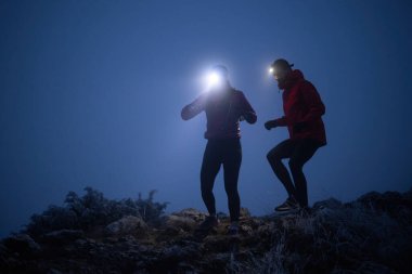 İki sporcu gece boyunca engebeli dağ patikalarında koşar, far ve kış giysileri giyerek, soğuk, sisli arazide kararlılık ve dayanıklılıkla yol alırlar..
