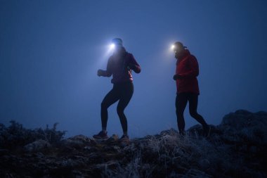 İki sporcu gece boyunca engebeli dağ patikalarında koşar, far ve kış giysileri giyerek, soğuk, sisli arazide kararlılık ve dayanıklılıkla yol alırlar..