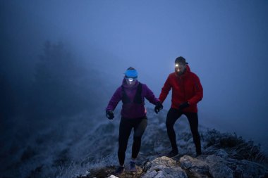 İki sporcu gece boyunca engebeli dağ patikalarında koşar, far ve kış giysileri giyerek, soğuk, sisli arazide kararlılık ve dayanıklılıkla yol alırlar..