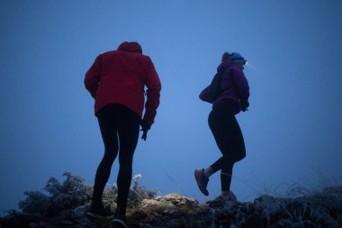 İki sporcu gece boyunca engebeli dağ patikalarında koşar, far ve kış giysileri giyerek, soğuk, sisli arazide kararlılık ve dayanıklılıkla yol alırlar..
