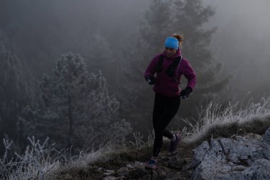 Bir dağda ultra-maraton koşusu için koşan bayan sporcu. Açık havada antrenman yapan koşucu bir kadın aktif ve zinde bir hayat sürüyor. Sabahın erken saatlerinde koşucular silueti.