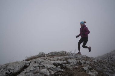 Bir dağda ultra-maraton koşusu için koşan bayan sporcu. Açık havada antrenman yapan koşucu bir kadın aktif ve zinde bir hayat sürüyor. Sabahın erken saatlerinde koşucular silueti.