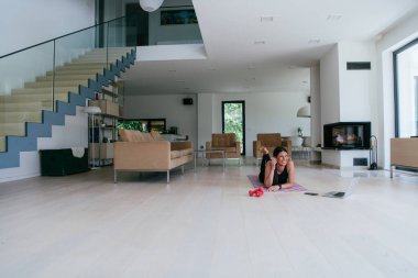 Genç bir kadın online eğitimden sonra oturma odasında yerde yatarken dinleniyor.