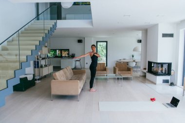 Genç Güzel Kadın Egzersiz, Esneme ve Egzersiz Yogası Parlak Sunny House 'da Video Çağrı Konferansı aracılığıyla Antrenörle. Sağlıklı Yaşam Tarzı, Refah ve Farkındalık Konsepti.