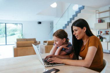 Anne ve kızı dizüstü bilgisayarda ailesi ve arkadaşlarıyla konuşuyorlardı. Büyük evin modern oturma odasında oturuyorlardı.