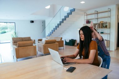 Anne ve kızı dizüstü bilgisayarda ailesi ve arkadaşlarıyla konuşuyorlardı. Büyük evin modern oturma odasında oturuyorlardı.